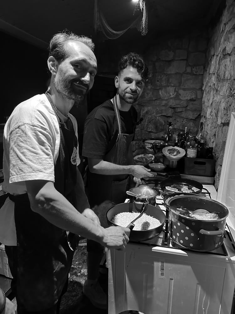A photograph of two team members smiling while cooking together