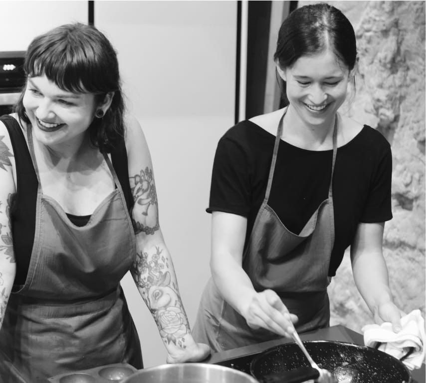 A photograph of two GitBook team members smiling while taking part in a cooking class
